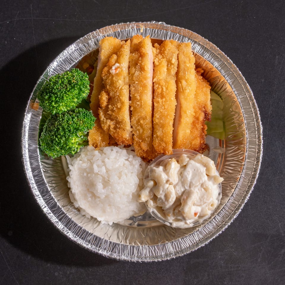 Crispy fried chicken cutlets, white rice, macaroni salad, and broccoli in a foil takeout container.